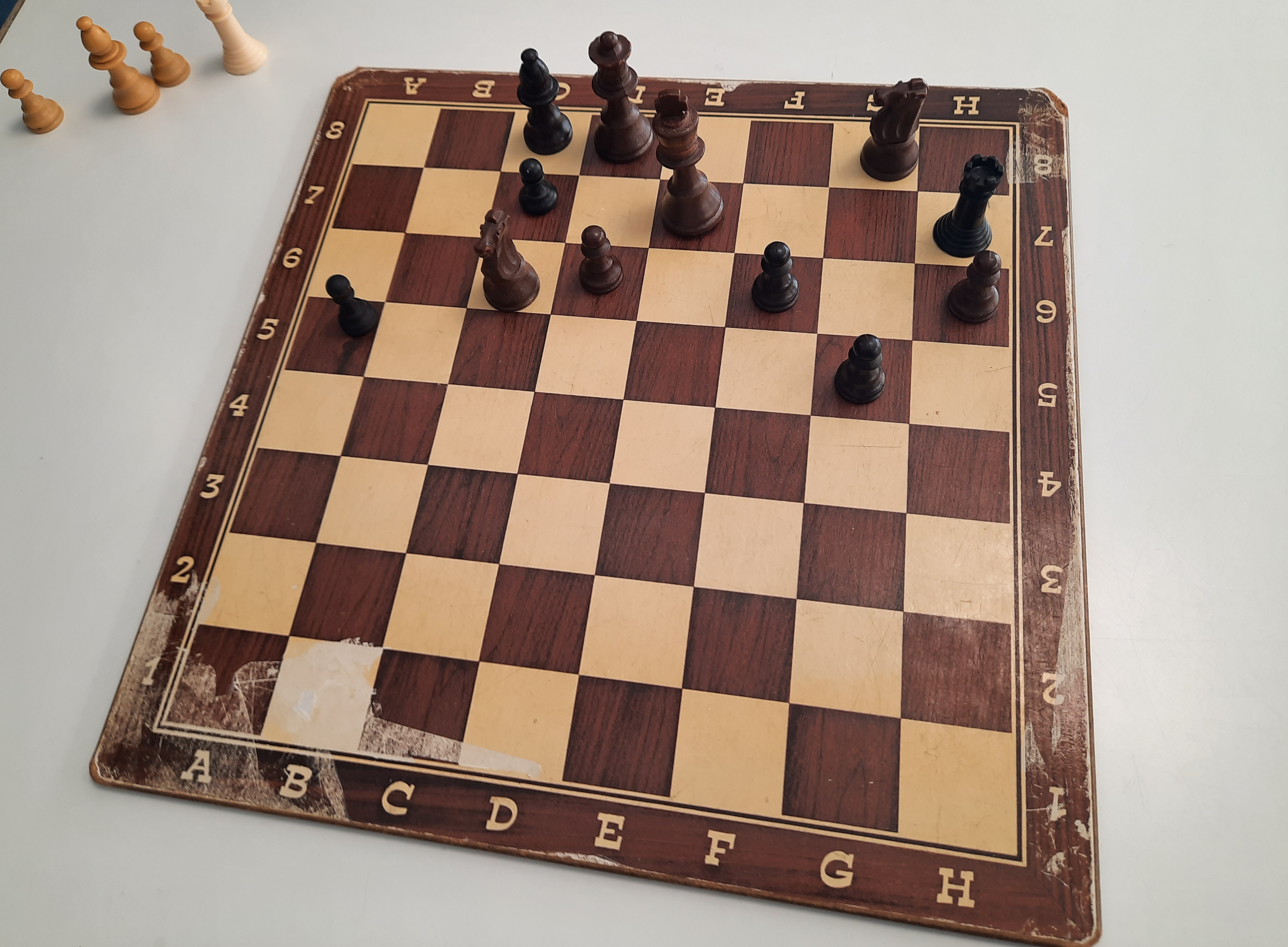 Black pieces on a board with a few white pieces captured off the the side